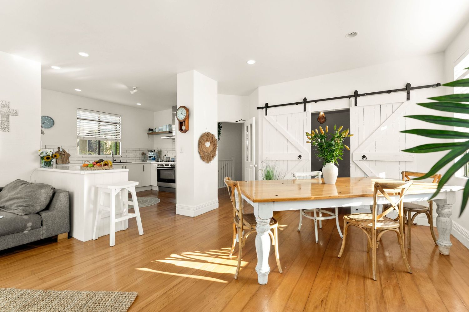Open concept modern white interior with hardwood floors features sliding barn door and minimal Scandinavian inspired decor.
