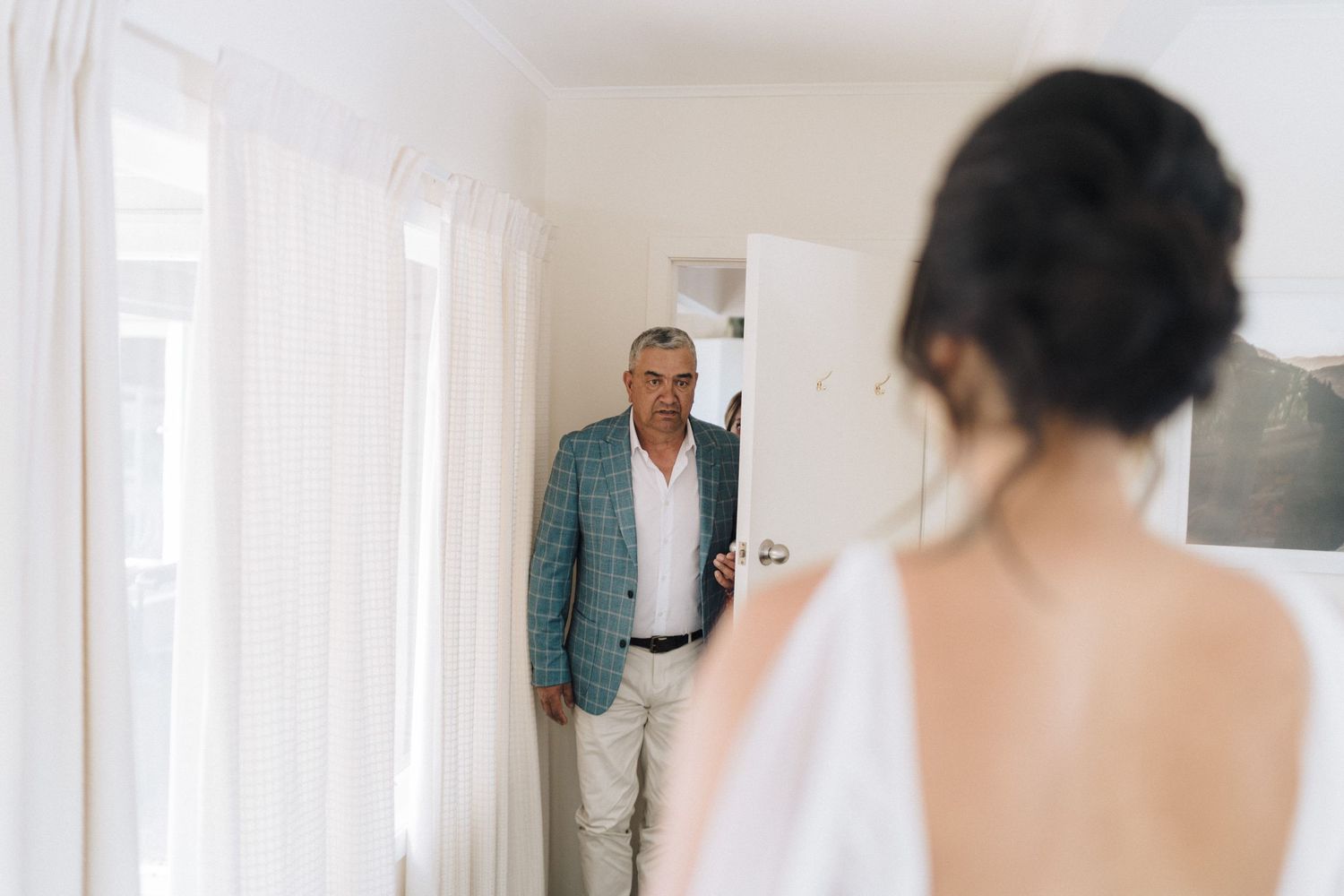 Intimate first look moments shared in a bright sunlit room before a wedding ceremony.