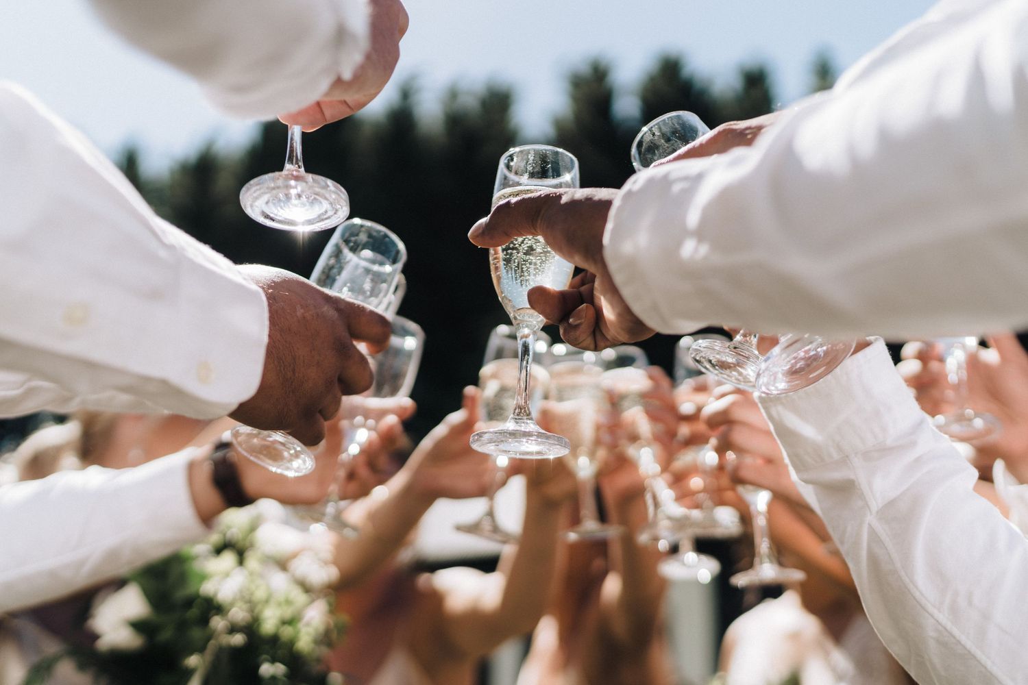Crystal wine glasses clink together in a celebratory toast at an elegant wedding reception.