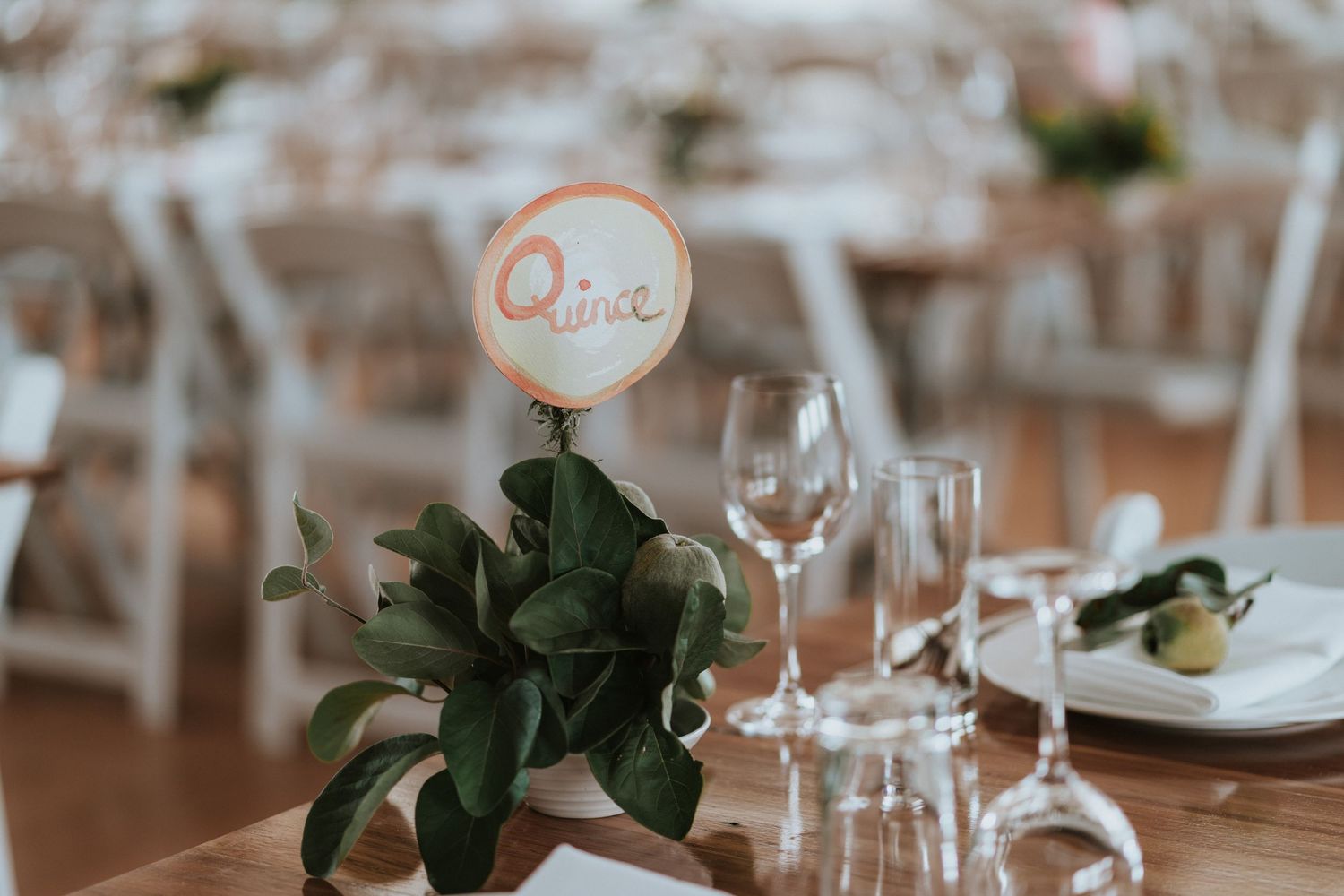 Elegant wedding reception table setting with wine glasses and floral centerpieces in a rustic venue.