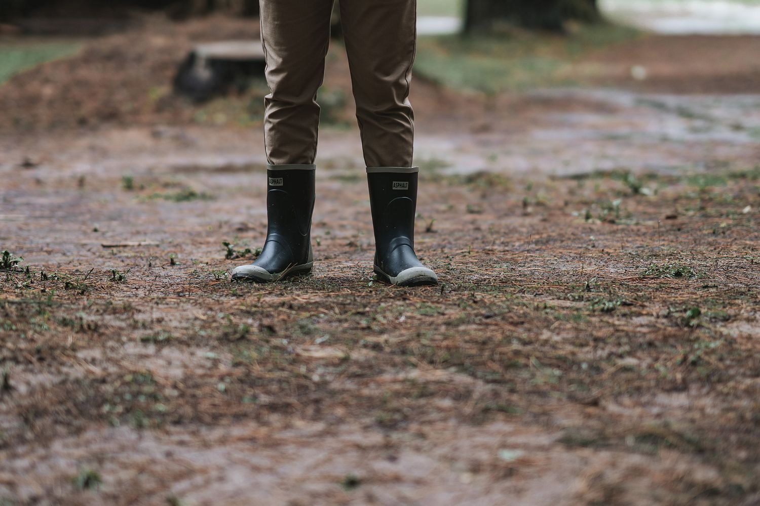 Close-up shot of muddy rain boots on wet ground during an autumn day.