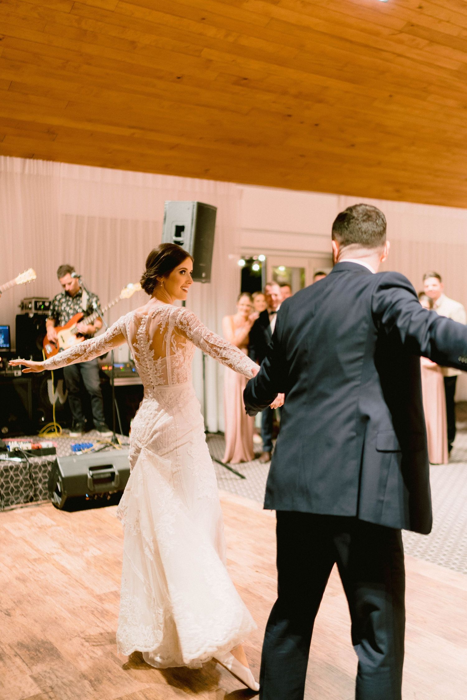 A couple performs their first dance at their wedding reception on a wooden dance floor.