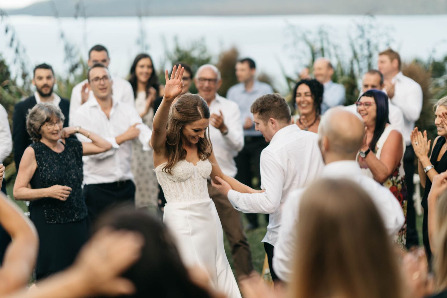 Wedding guests dance together joyfully at an outdoor reception celebration.