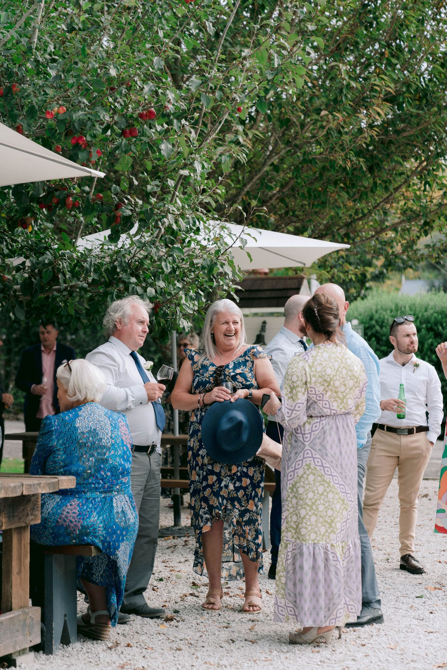 Wedding guests mingling under string lights at outdoor garden reception.