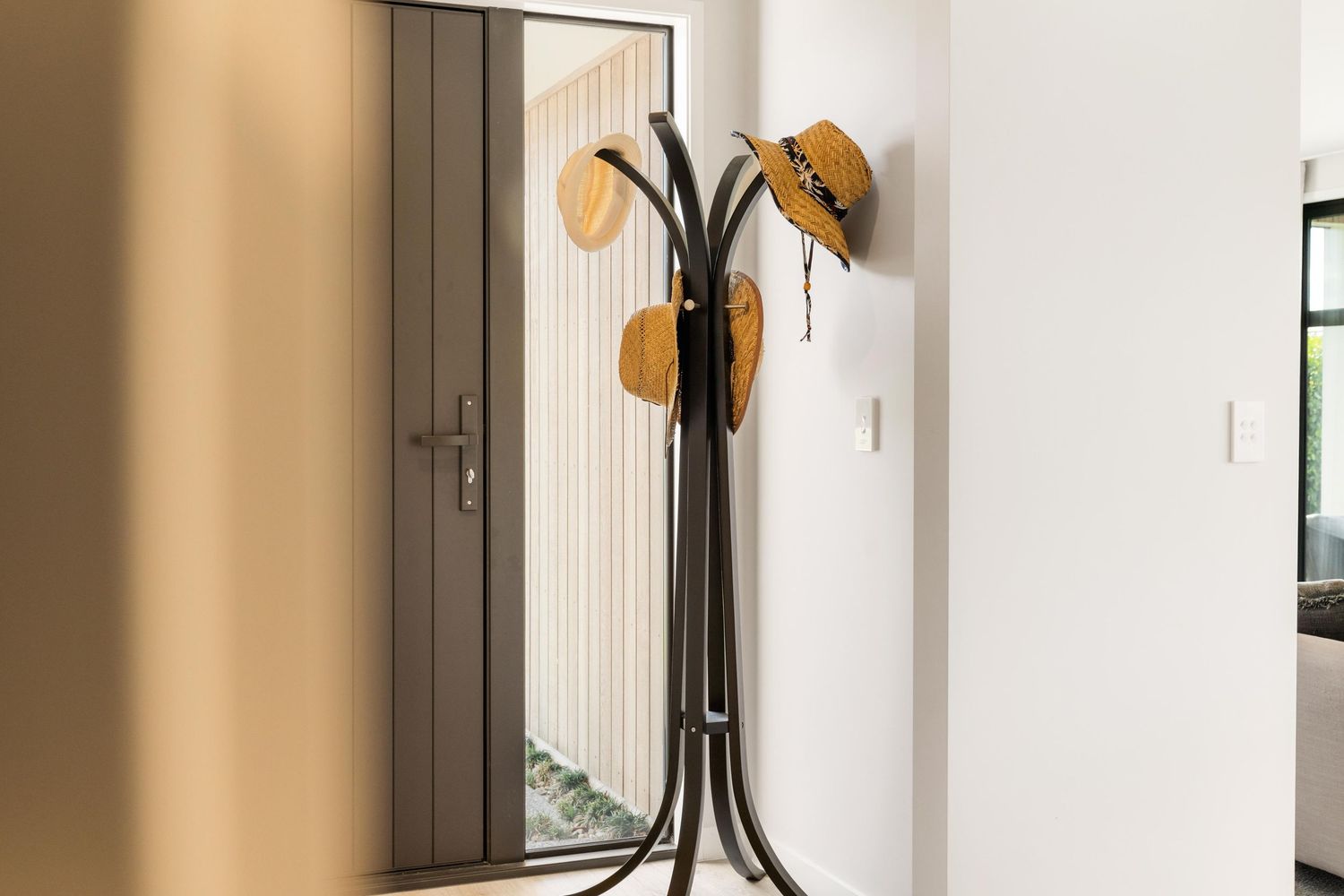White hallway with wall-mounted coat hooks and golden lighting fixtures against minimalist interior design.