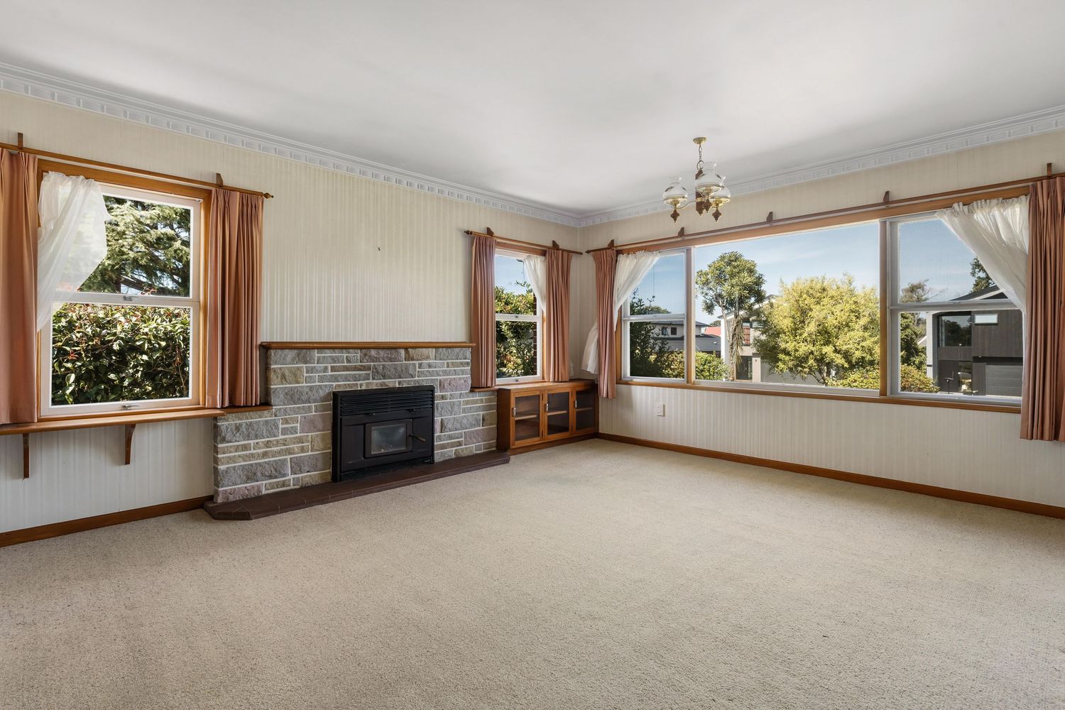 Panoramic view of a spacious living room interior with brick fireplace and large windows.