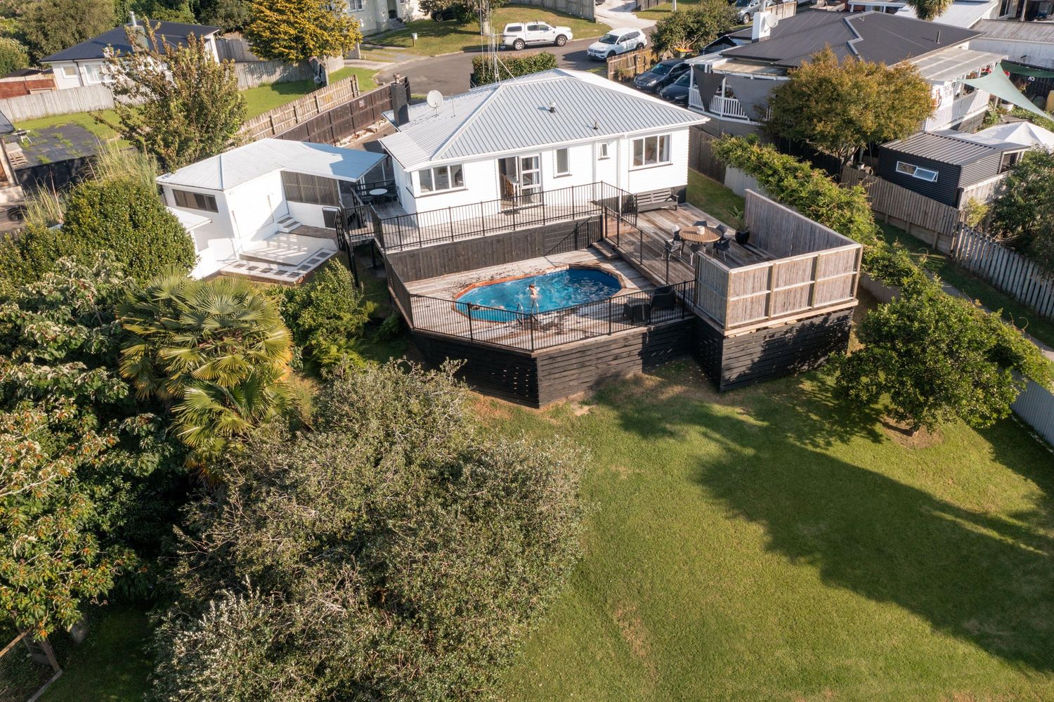 Aerial view of white residential property with swimming pool and landscaped yard.