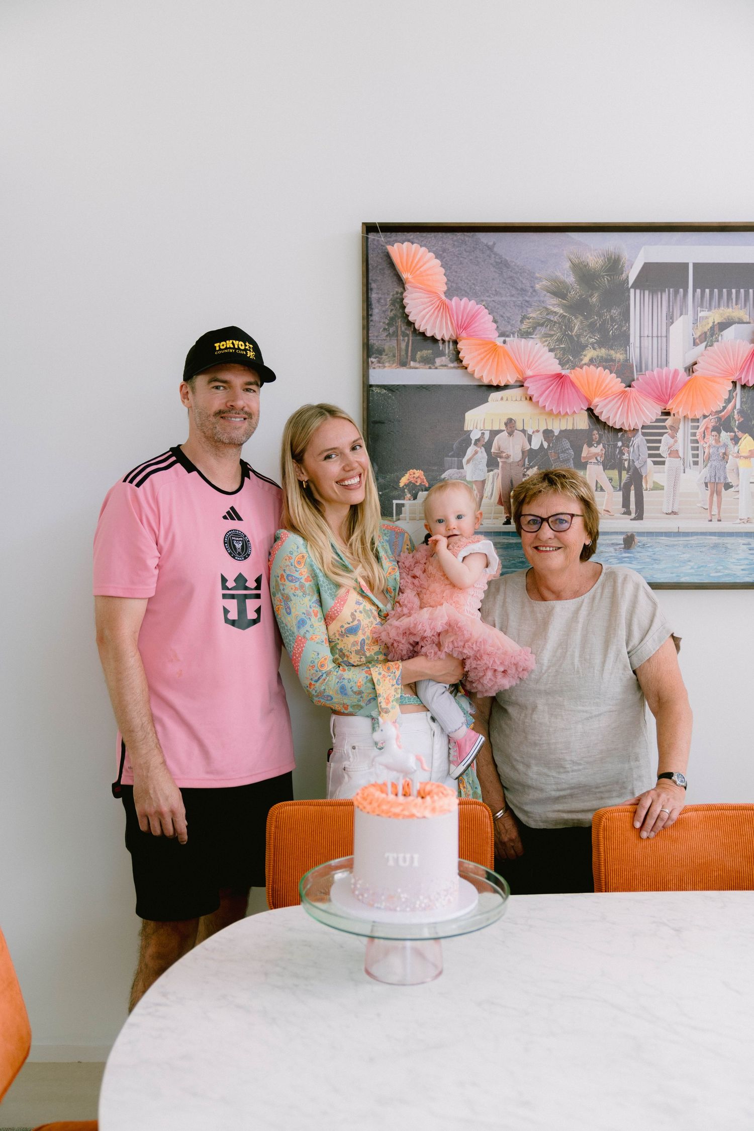 A sequence of photos shows a family gathering around a pink and white birthday cake with paper wing decorations.
