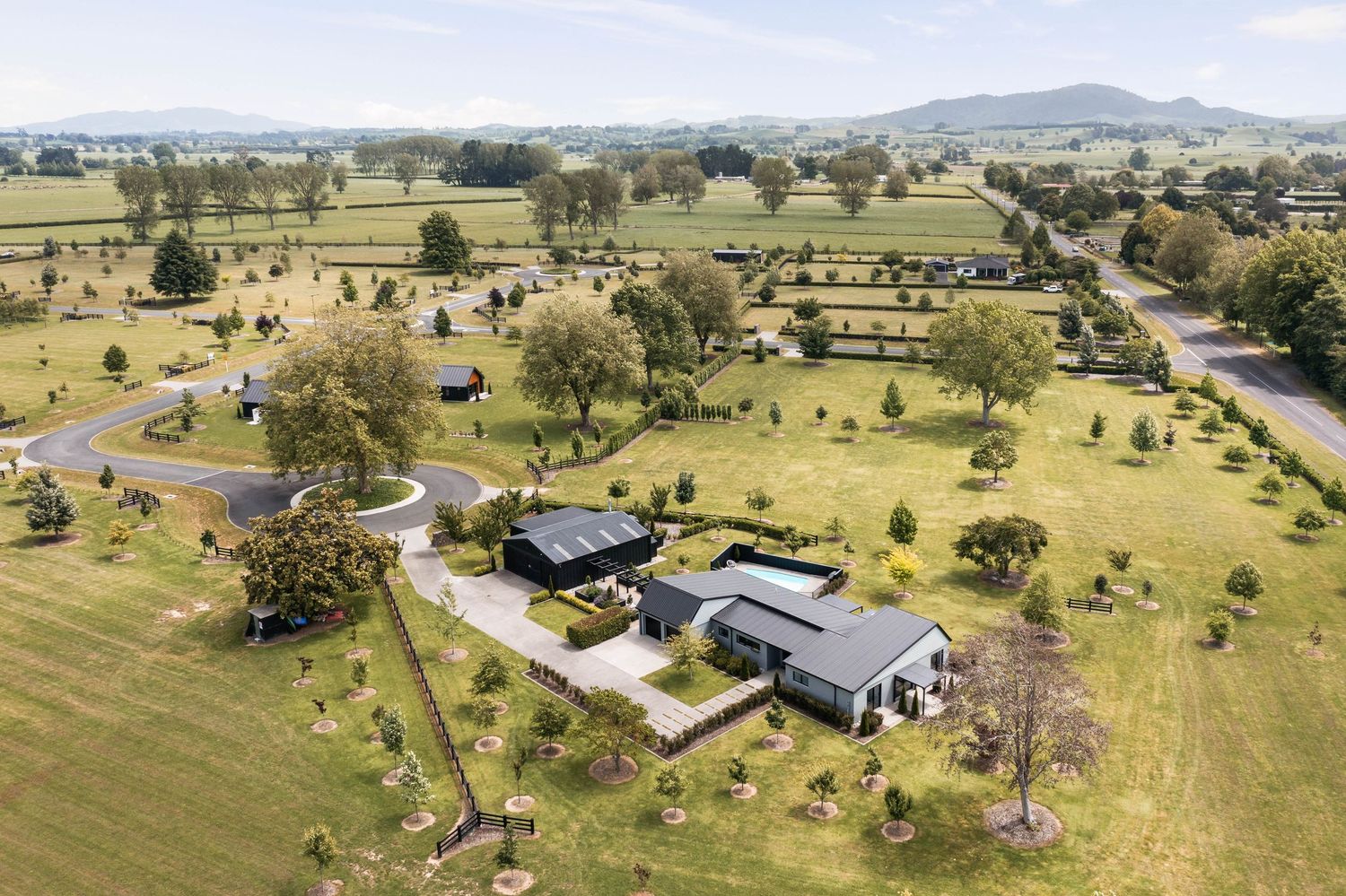 Aerial shots of a large rural property with farm buildings and scattered trees across rolling green pasture land.