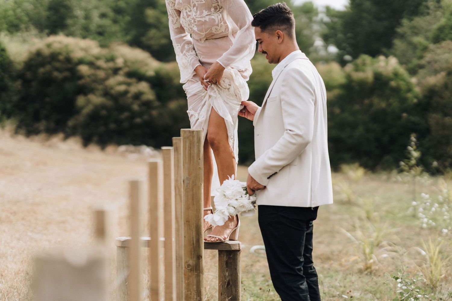 Romantic couple moment at rustic fence during outdoor wedding photoshoot.