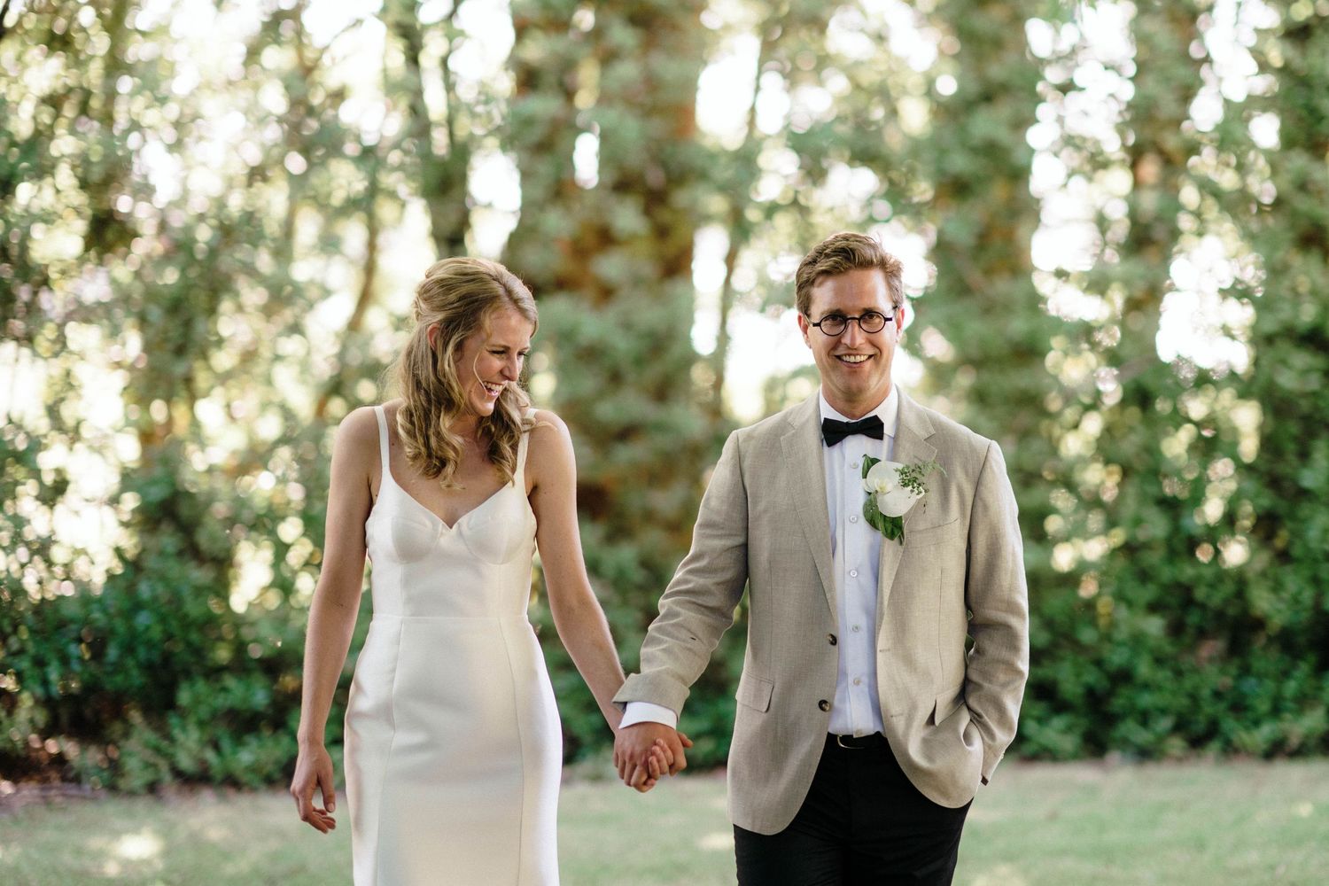 Happy couple walking together in a wooded area during golden hour.