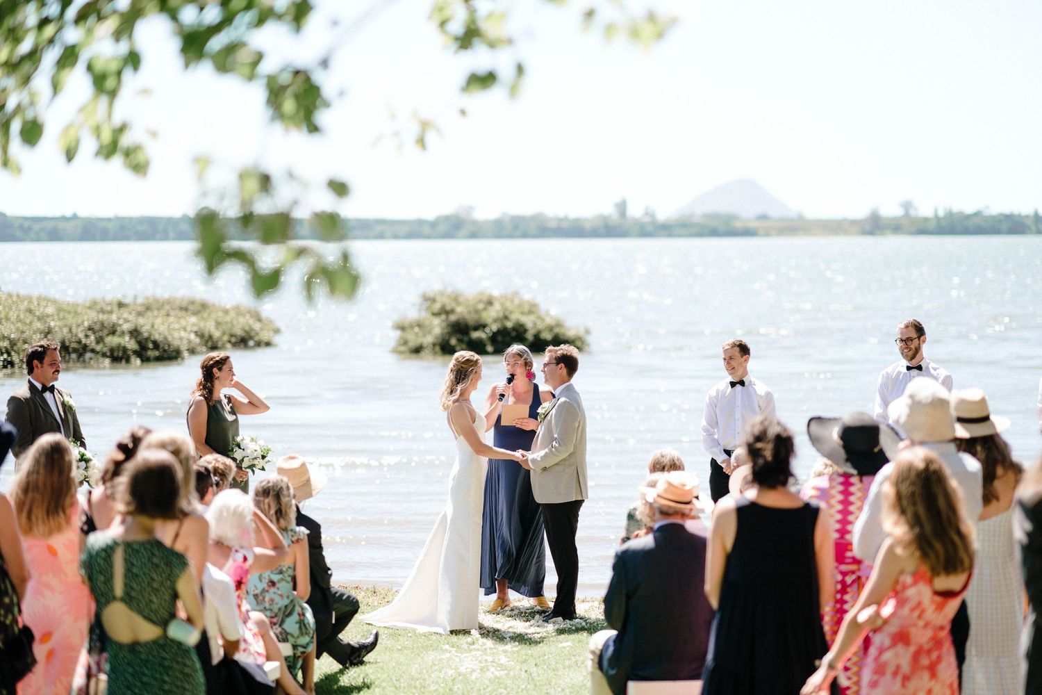 Wedding celebration by the waterfront with guests gathered on a sunny afternoon.
