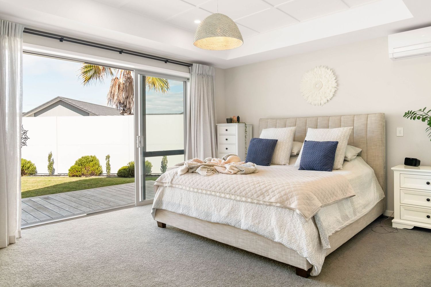 Luxurious master bedroom with white bedding, coastal decor and natural light.