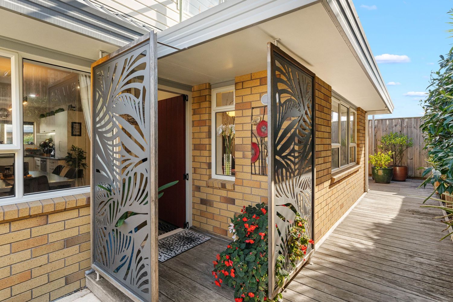 Panoramic view of a modern home's exterior walkway with decorative metal railings and tiled floor under natural lighting.
