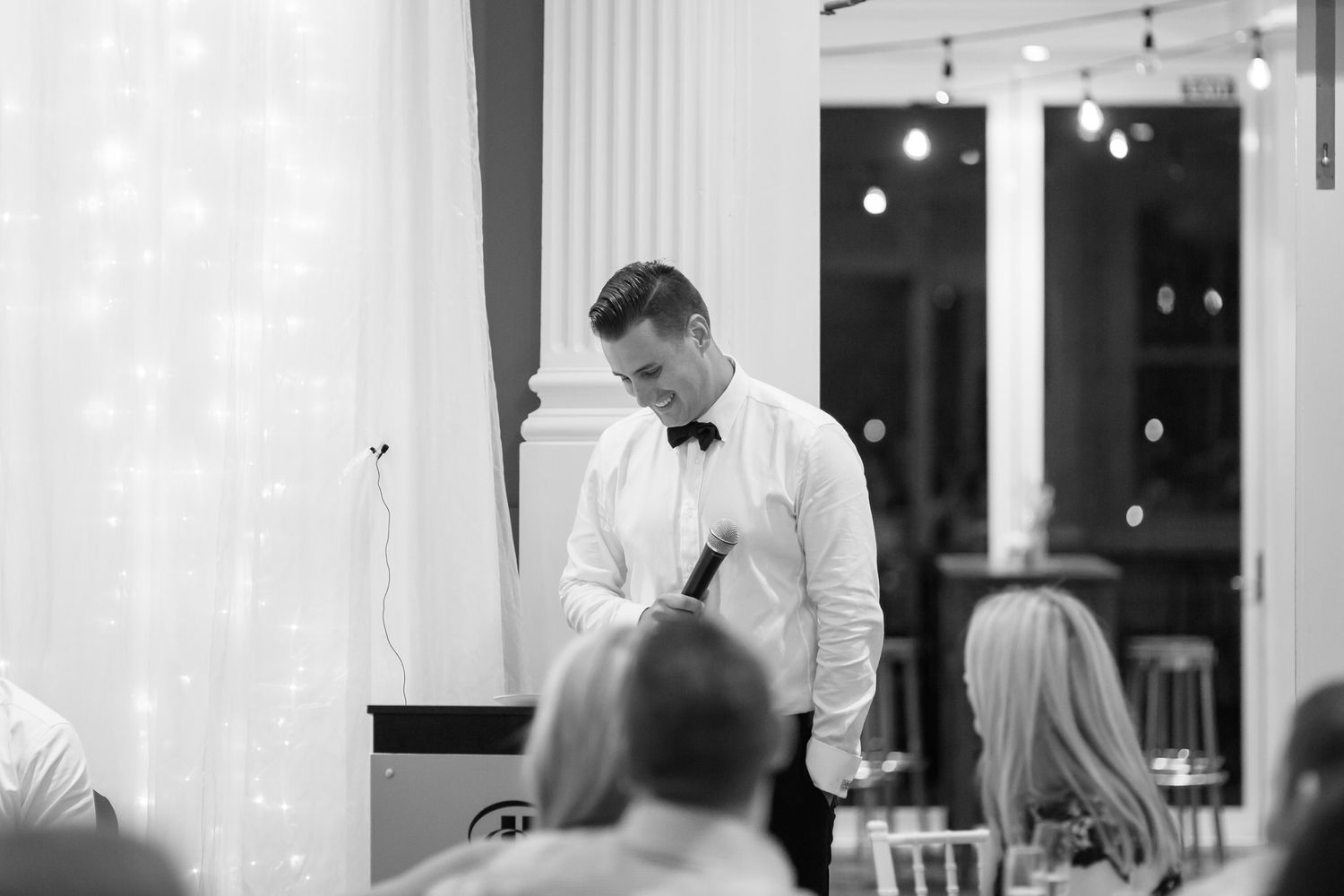 Restaurant servers in formal attire carry plates of food through an elegant dining room during dinner service.