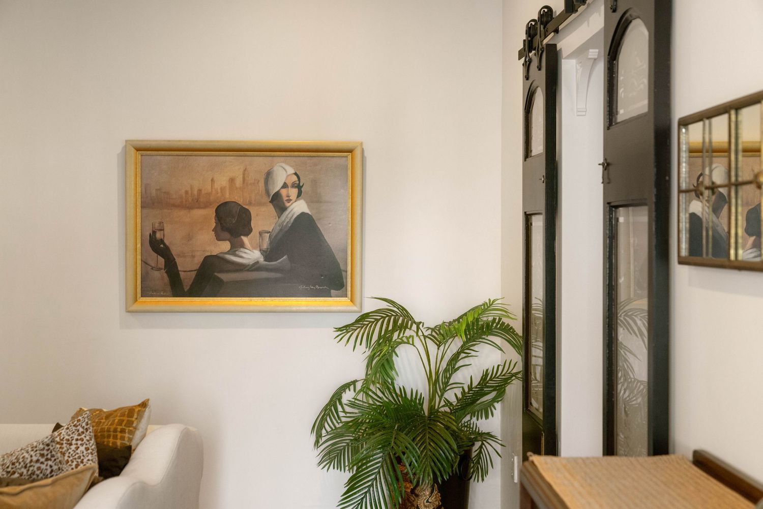 Modern interior hallway with tropical plants, framed artwork, and sophisticated lighting fixtures.