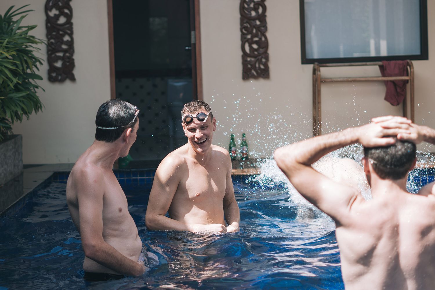 People enjoying leisure time in a swimming pool with blue water on a sunny day.