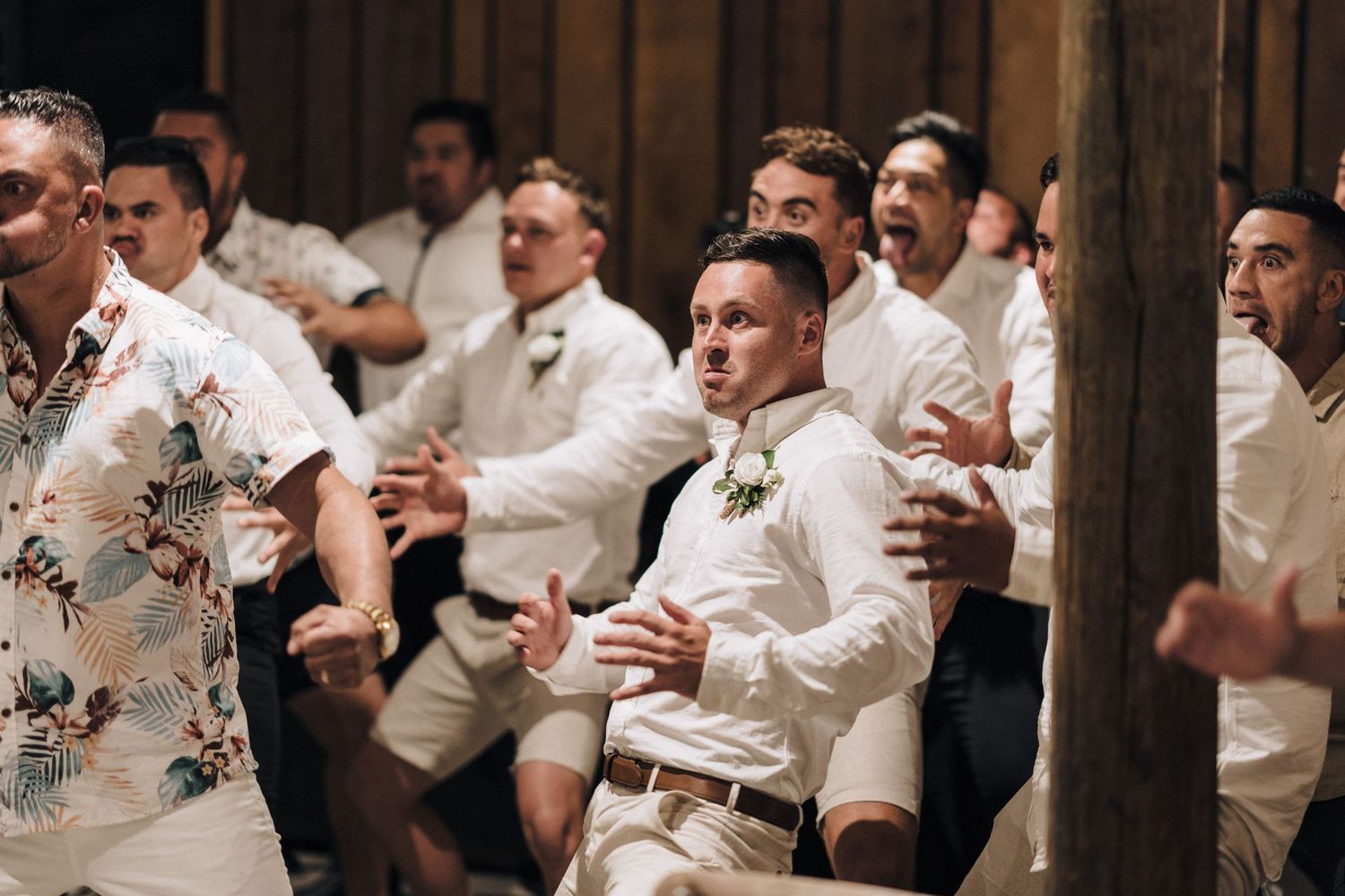 Groomsmen in white shirts and khakis celebrate during wedding festivities.