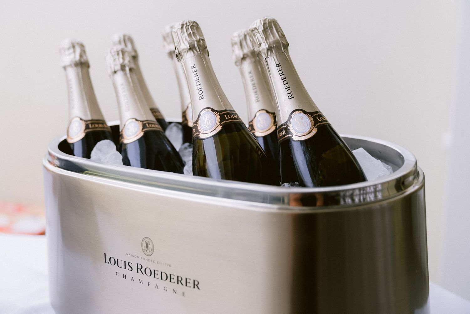 Row of Louis Roederer champagne bottles chilling in an elegant black ice bucket.