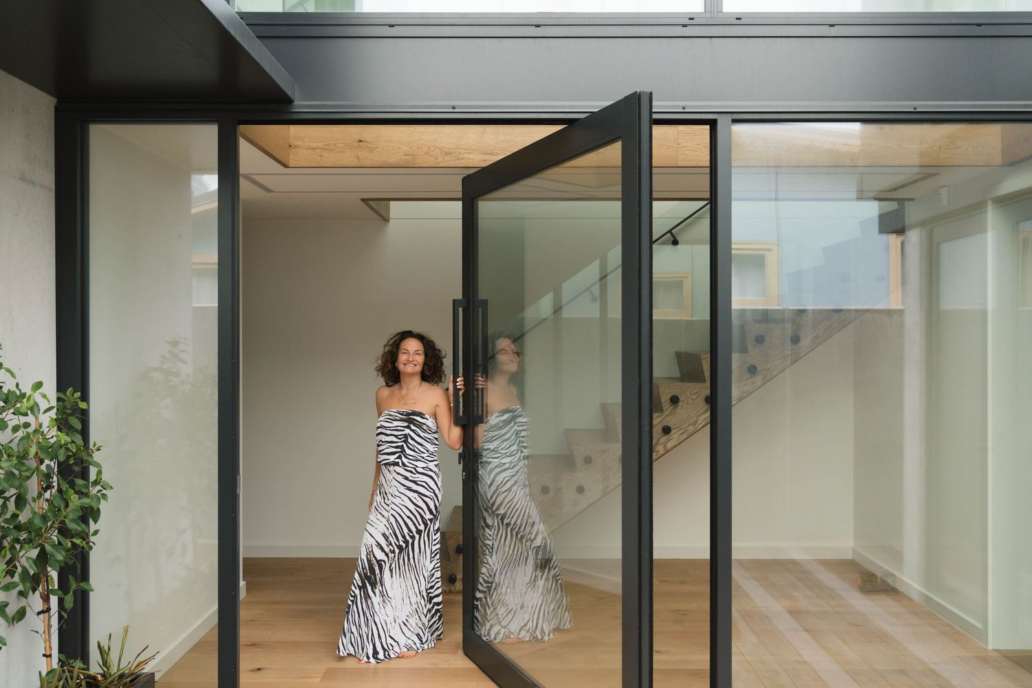 Modern open concept interior with floor-to-ceiling windows and indoor plants.