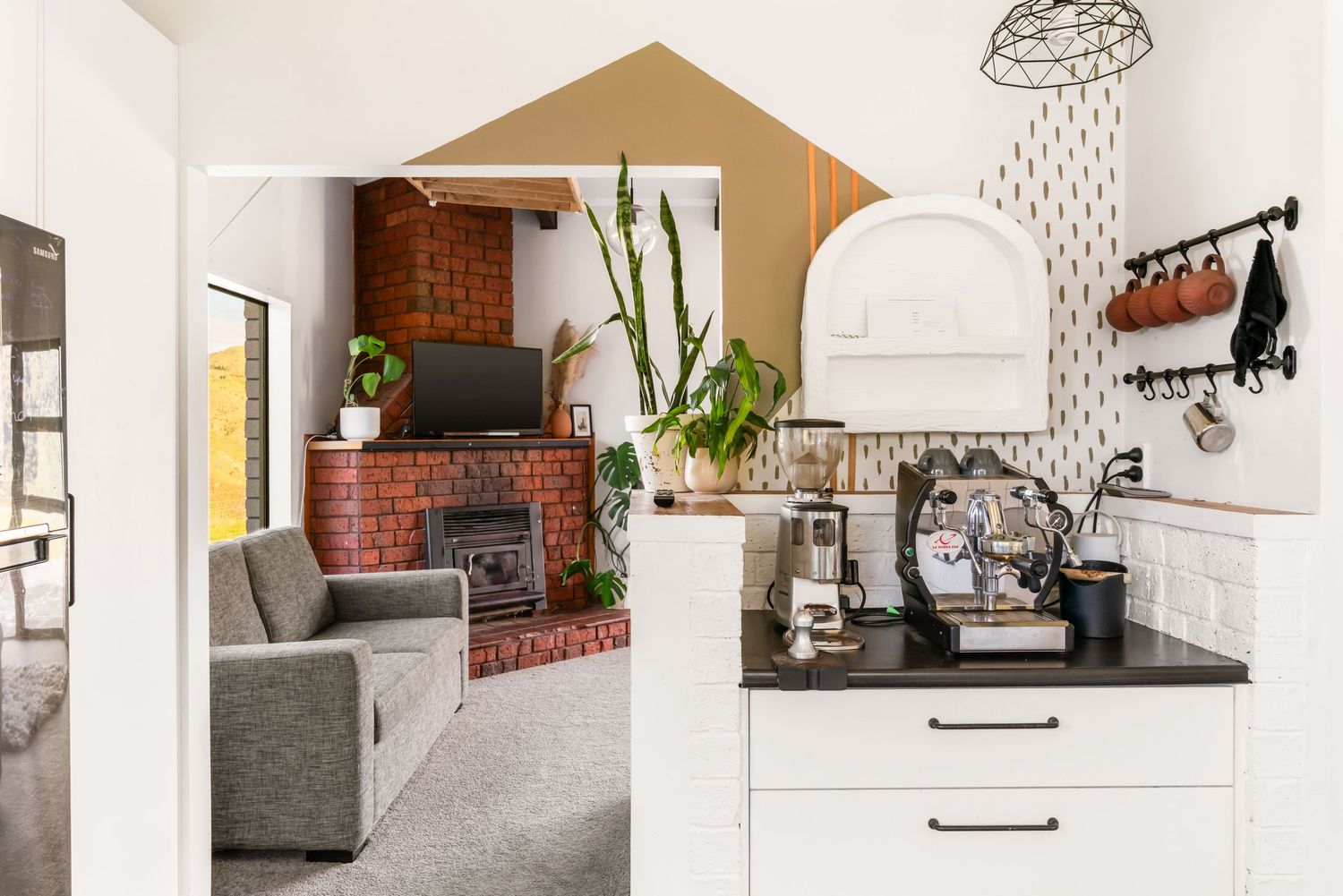 Contemporary kitchen with white cabinets, brick accent wall, and indoor plants.