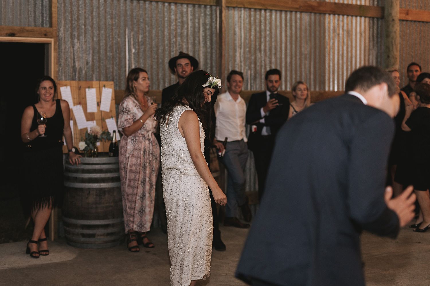 Guests enjoy a casual celebration in an industrial-style venue with rustic wine barrels and metal walls.