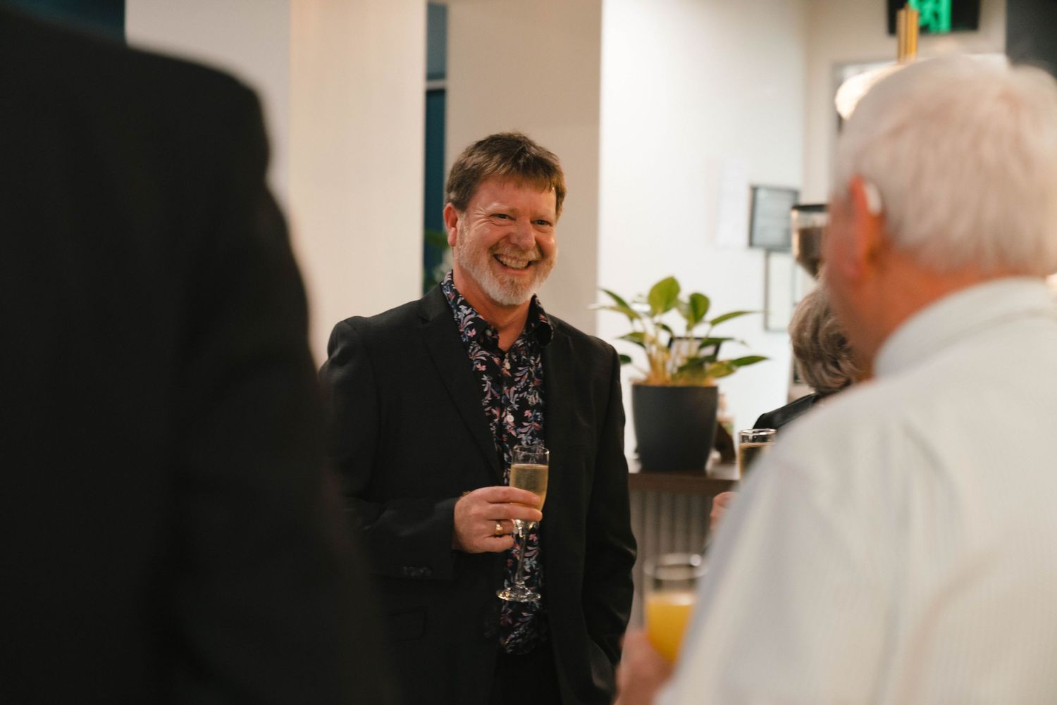 Two people engaged in lively conversation at a social gathering while holding drinks.
