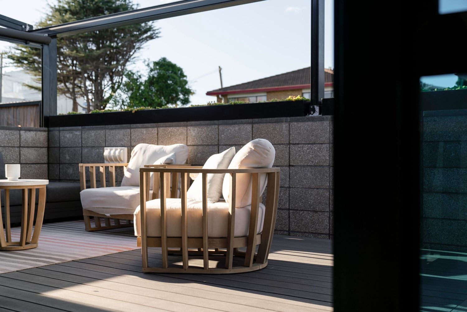 Modern outdoor terrace with sleek lounge chairs and wood accents framed by black beams and city views.