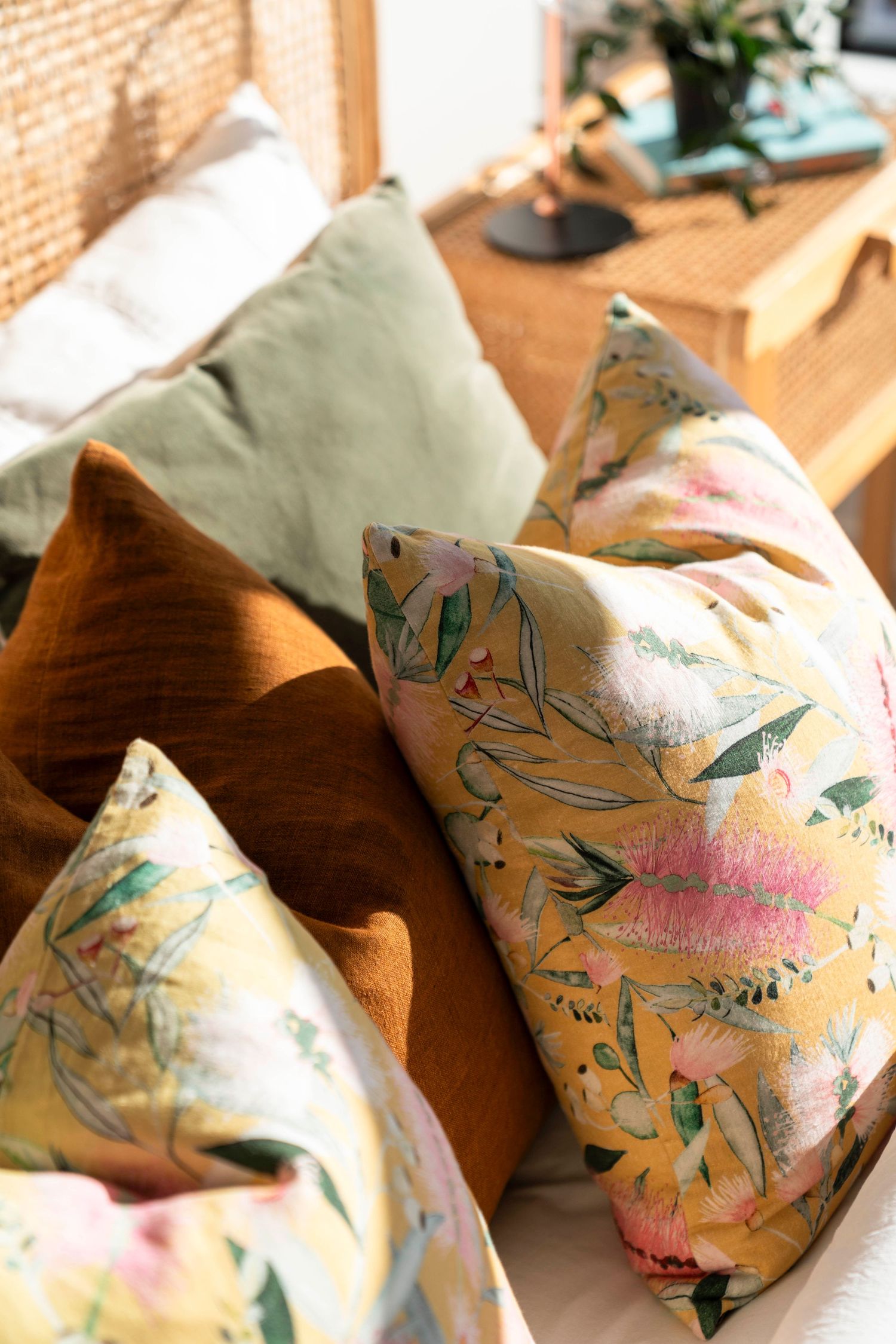 Decorative throw pillows in olive green and floral patterns on wooden furniture.