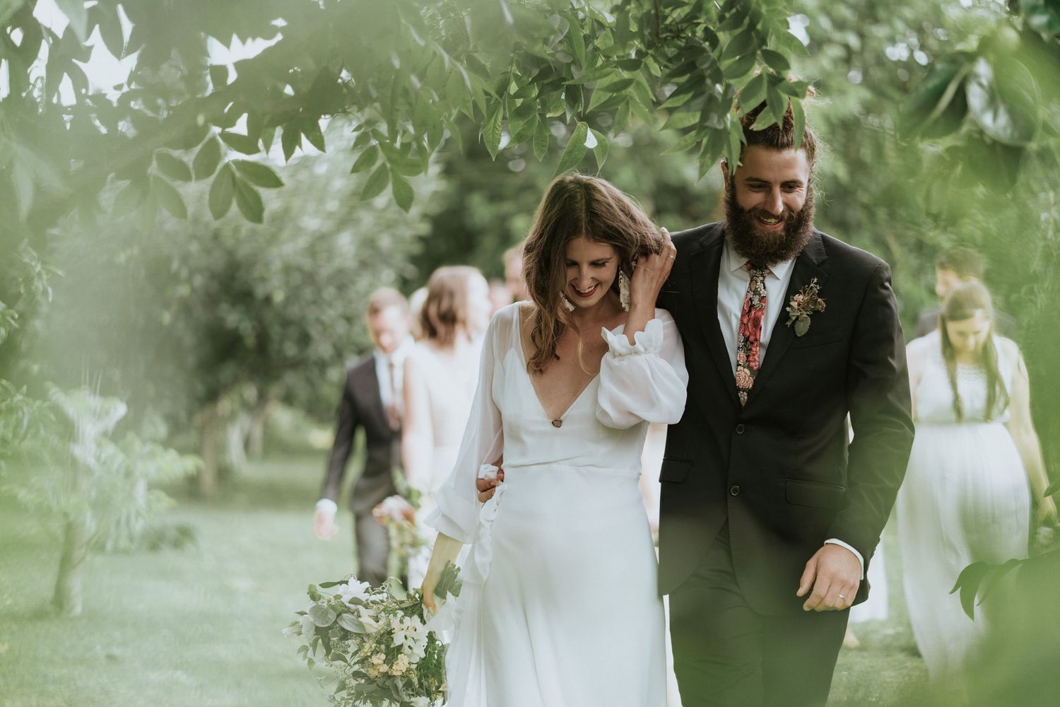 A couple shares intimate moments during an outdoor wedding celebration in a lush garden setting.