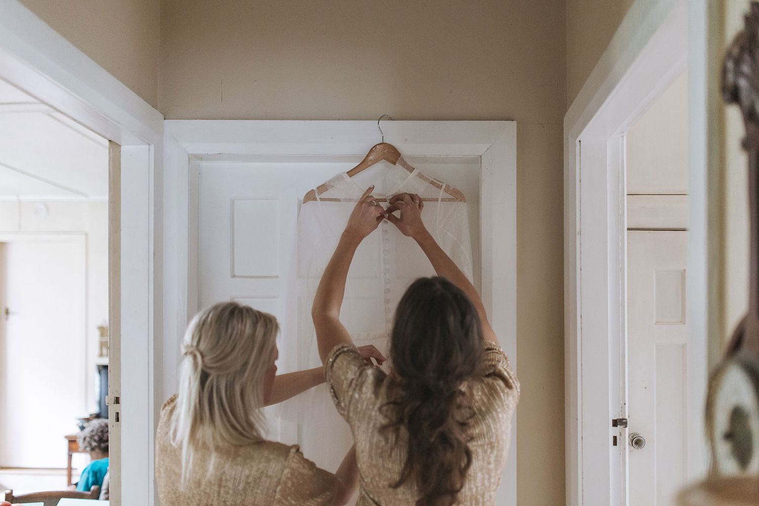 A woman in loose clothing practices dance movements in a sequence across a hallway with white walls and doors.