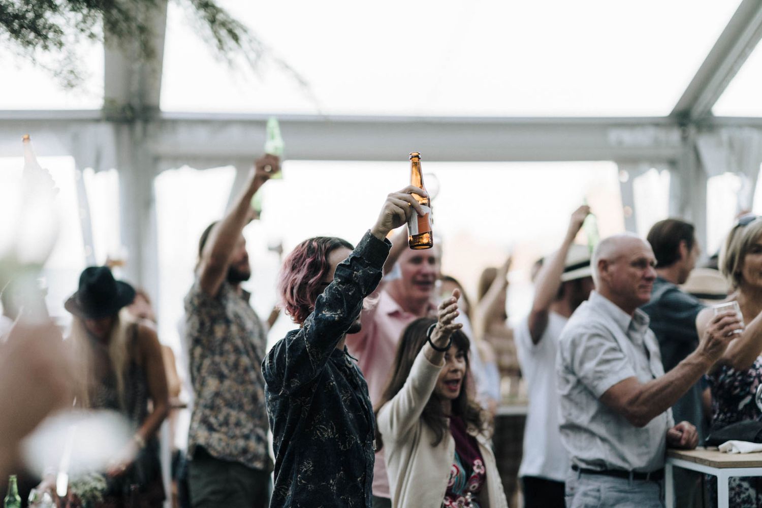 Crowd of excited business professionals celebrating with raised arms during a corporate event.