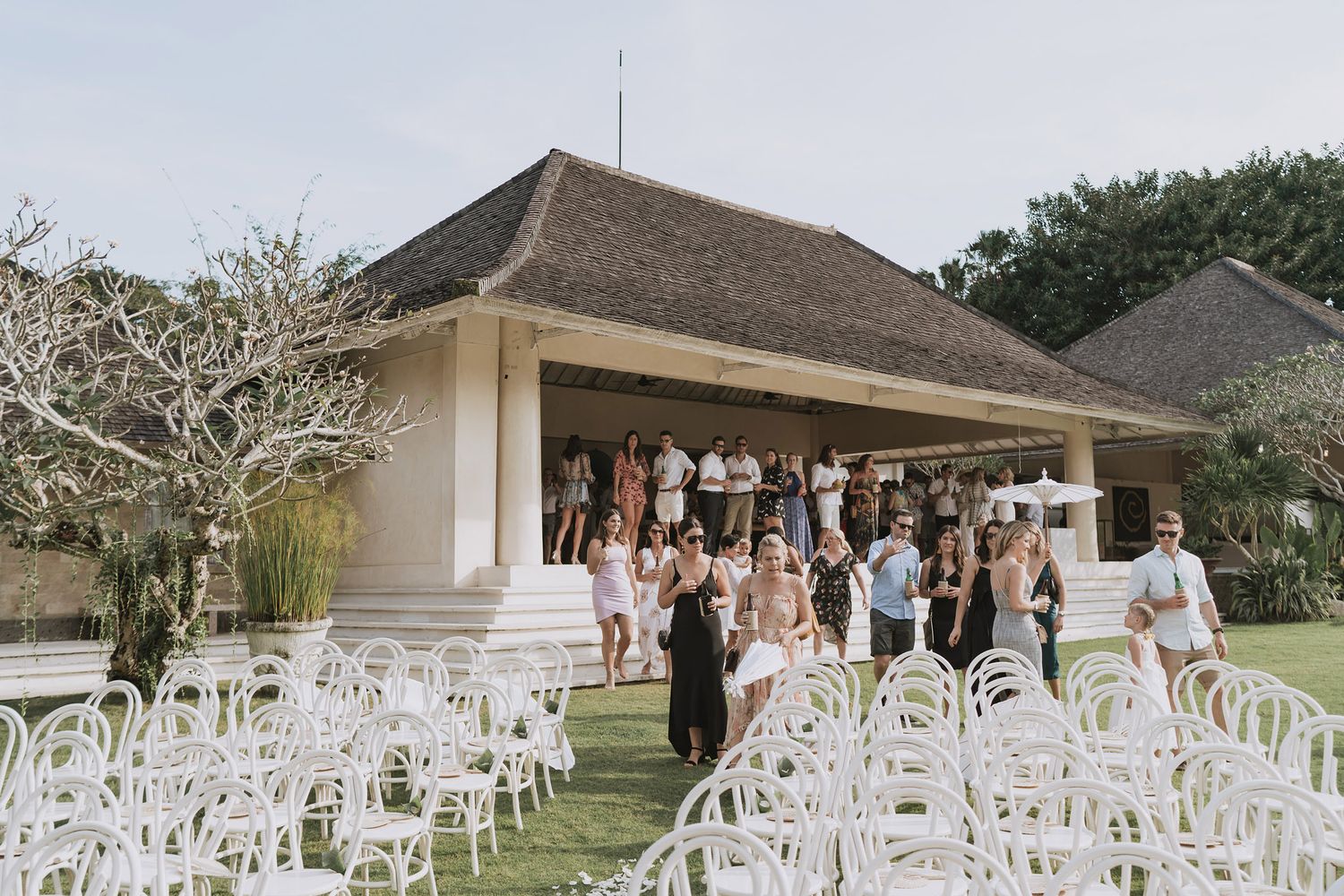 Wedding ceremony setup with white chairs arranged outdoors in front of a covered pavilion structure.