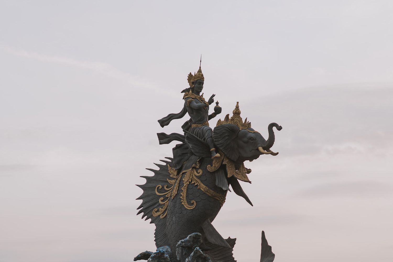Dramatic silhouette of an ornate statue depicting a warrior on horseback against a dusky sky.