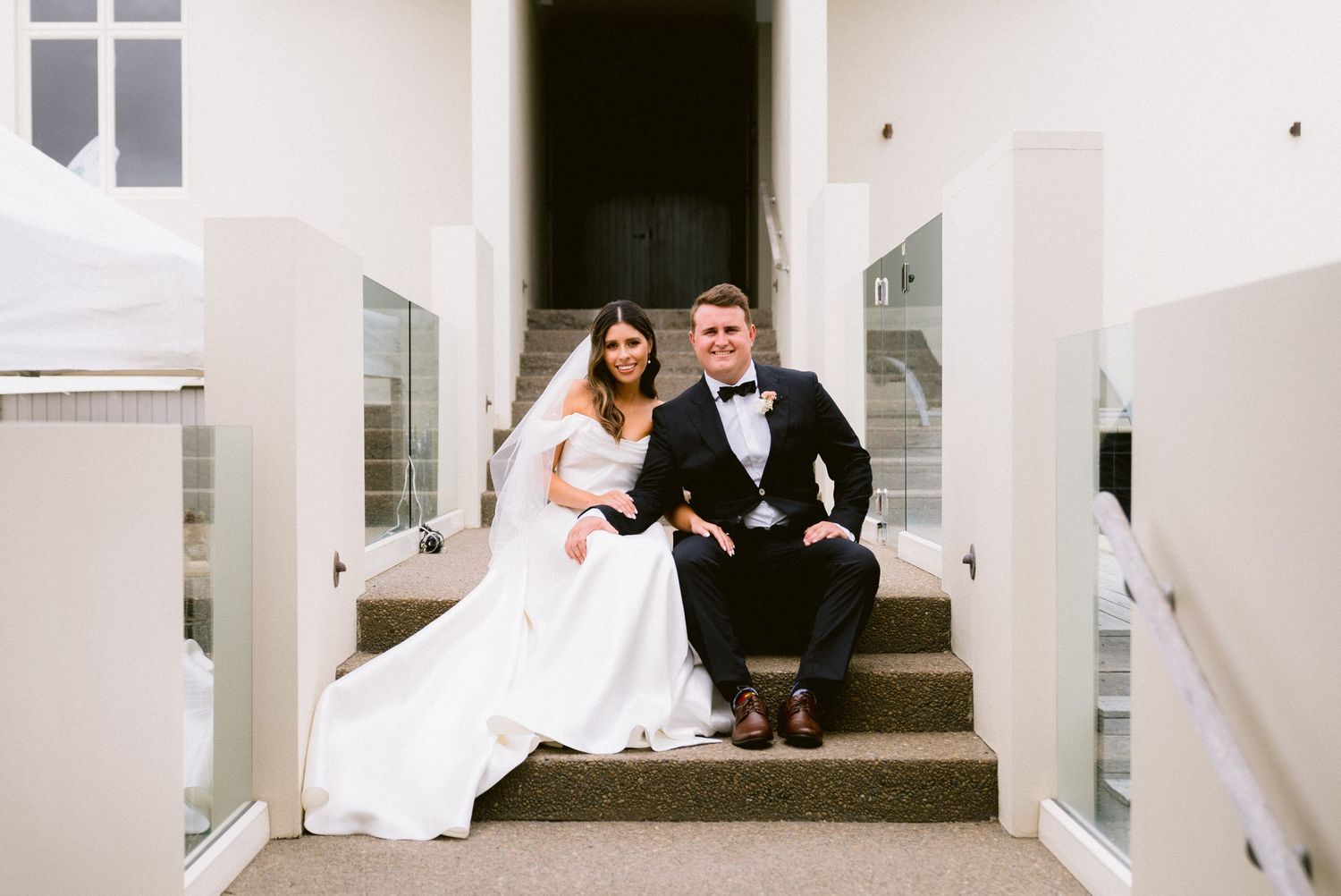 Newlyweds posing together on white steps during their wedding celebration.