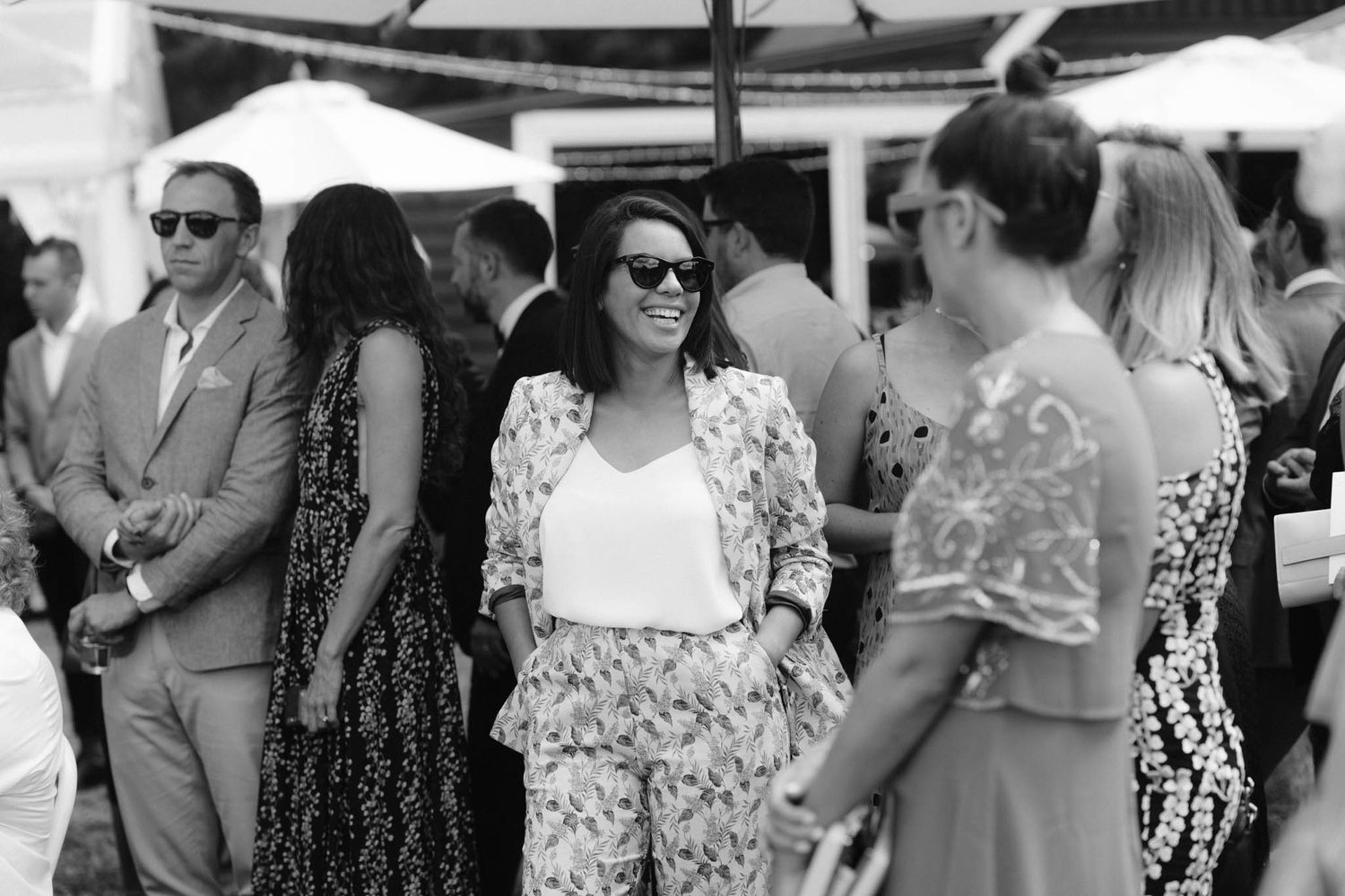 People browse displays and socialize at an outdoor market or street fair on a sunny day during summer.