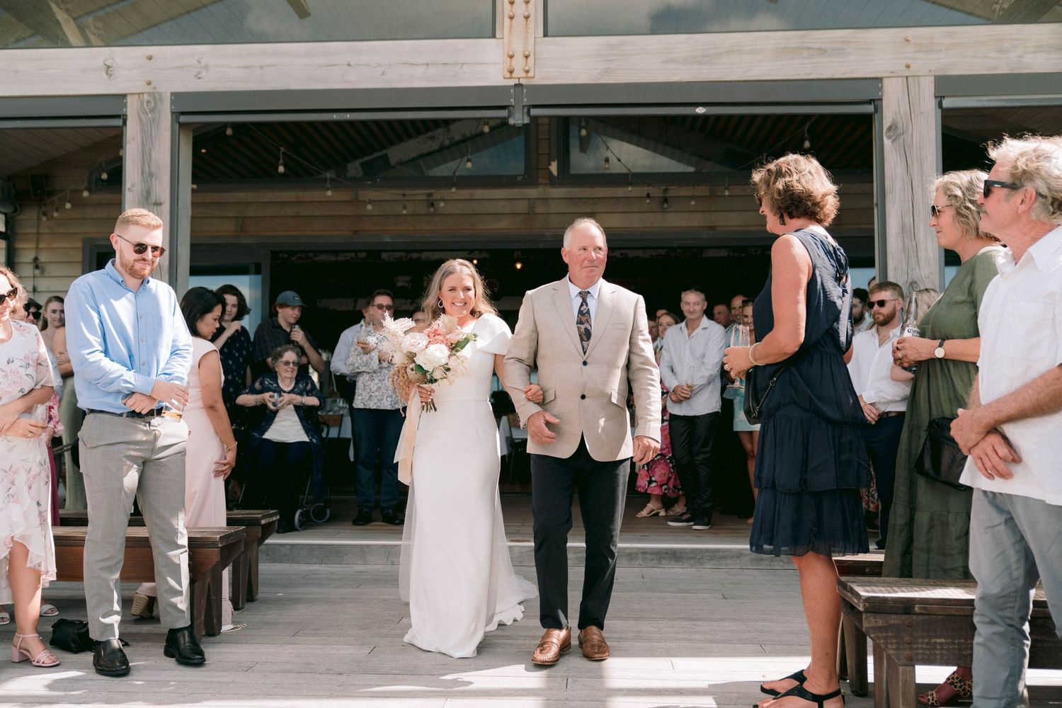 Guests watch as a couple enters their wedding reception space.