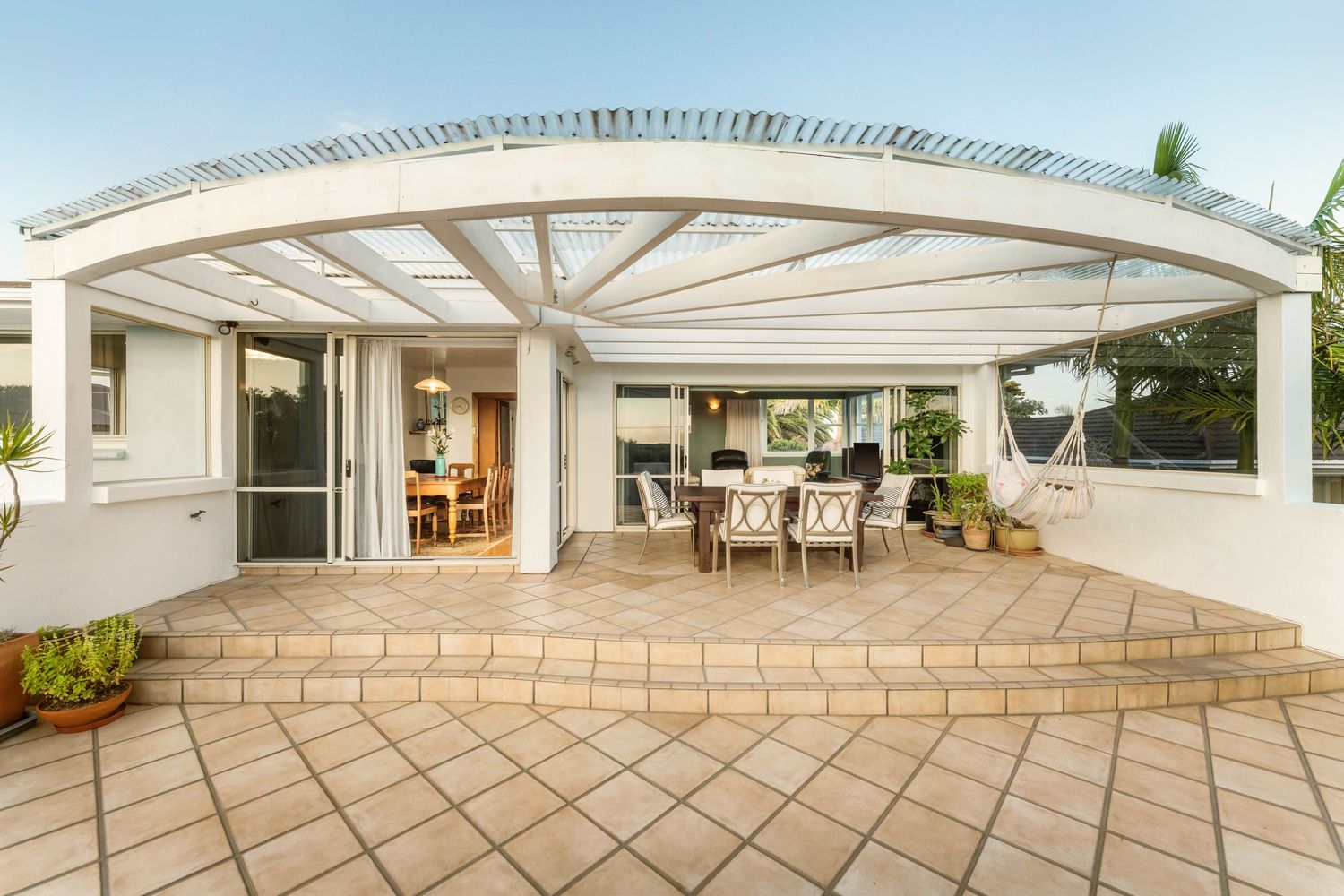 Panoramic view of a spacious outdoor terrace with white architectural elements and stone tiling.