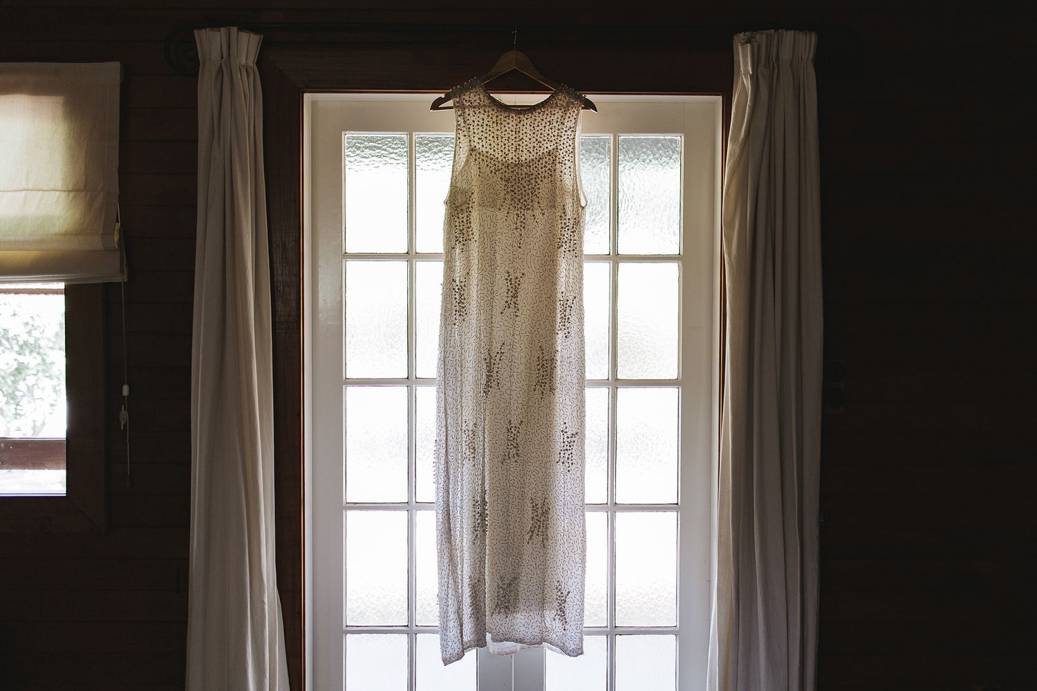 A series of four interior window frames with sheer white curtains in a dimly lit room creating an atmospheric scene.