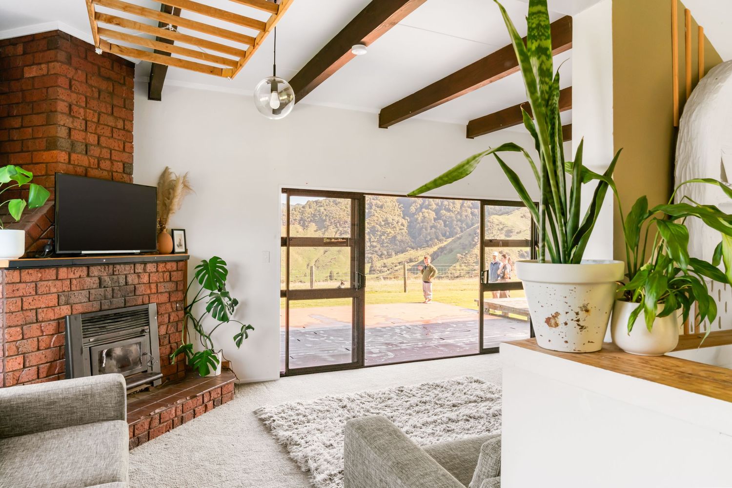 Modern farmhouse interior with exposed wooden beams, brick walls, and natural light.