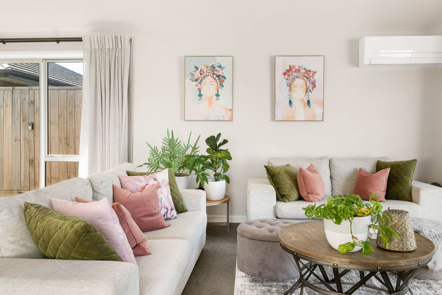 Bright living room with pink accent pillows, green plants and modern coastal artwork.