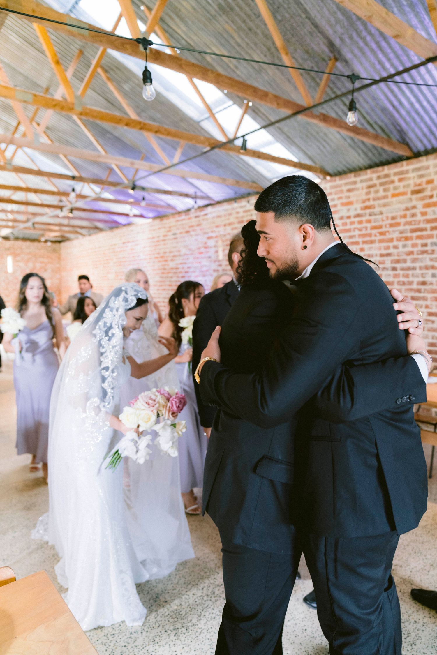 Wedding ceremony in a rustic brick venue with exposed wooden beams and gathered guests.