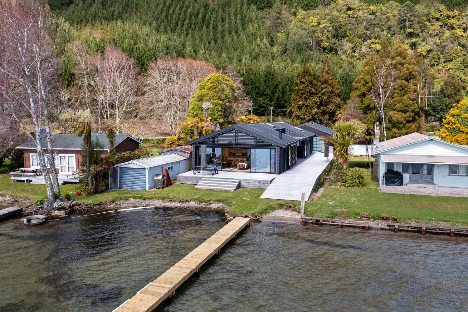 Aerial view showing residential properties with private docks along a serene lakefront surrounded by evergreen forest.