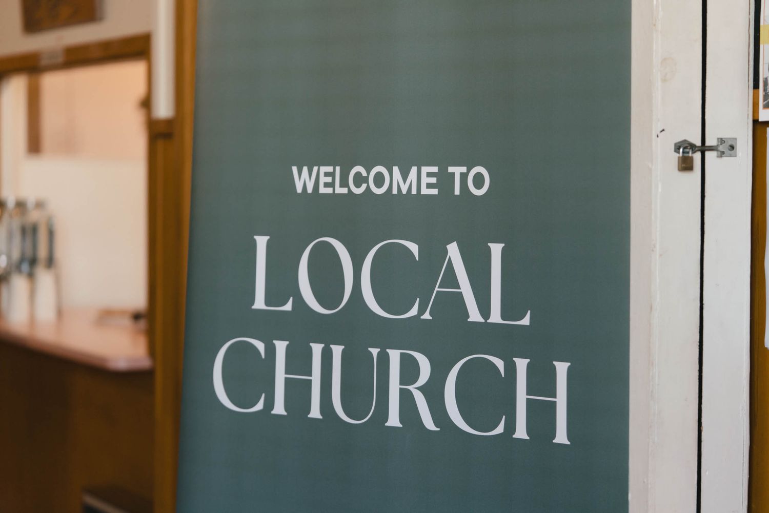 Vintage style green and white church welcome signs mounted on wood paneled walls in soft lighting.