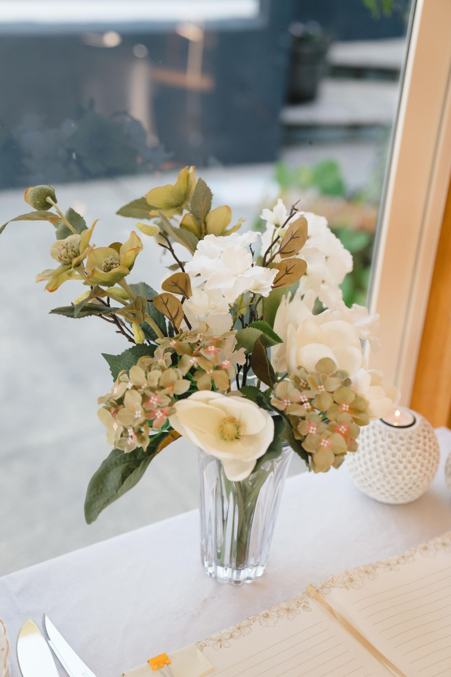 Delicate white floral arrangements in glass vases displayed on a white surface with natural lighting.