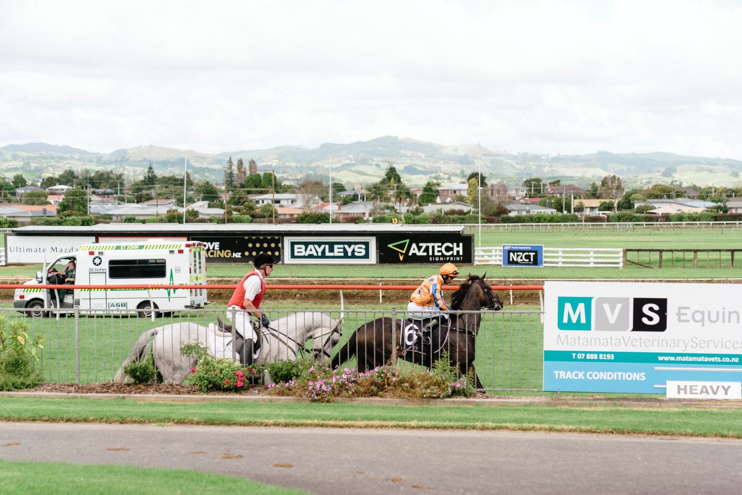 Panoramic view of a horse racing track with mountains in the background.