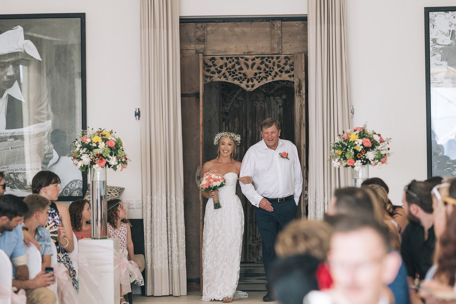 Indoor wedding ceremony with guests seated in elegant room with curtains.