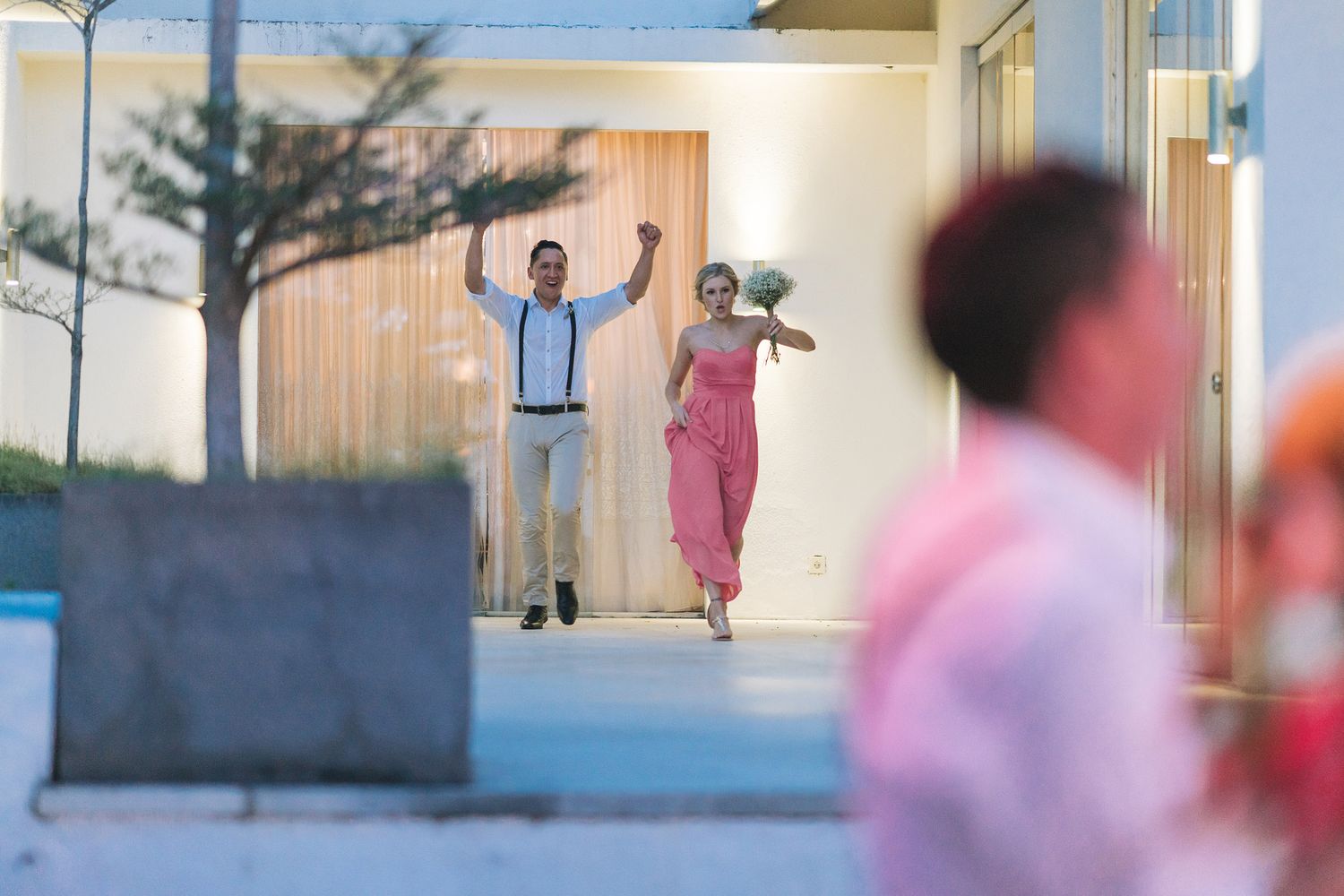 Wedding guests dance and celebrate in an outdoor venue at sunset.