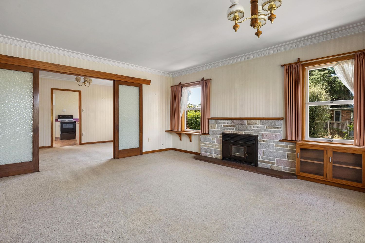 Spacious living room with white walls, brown trim molding, and large windows overlooking residential views.