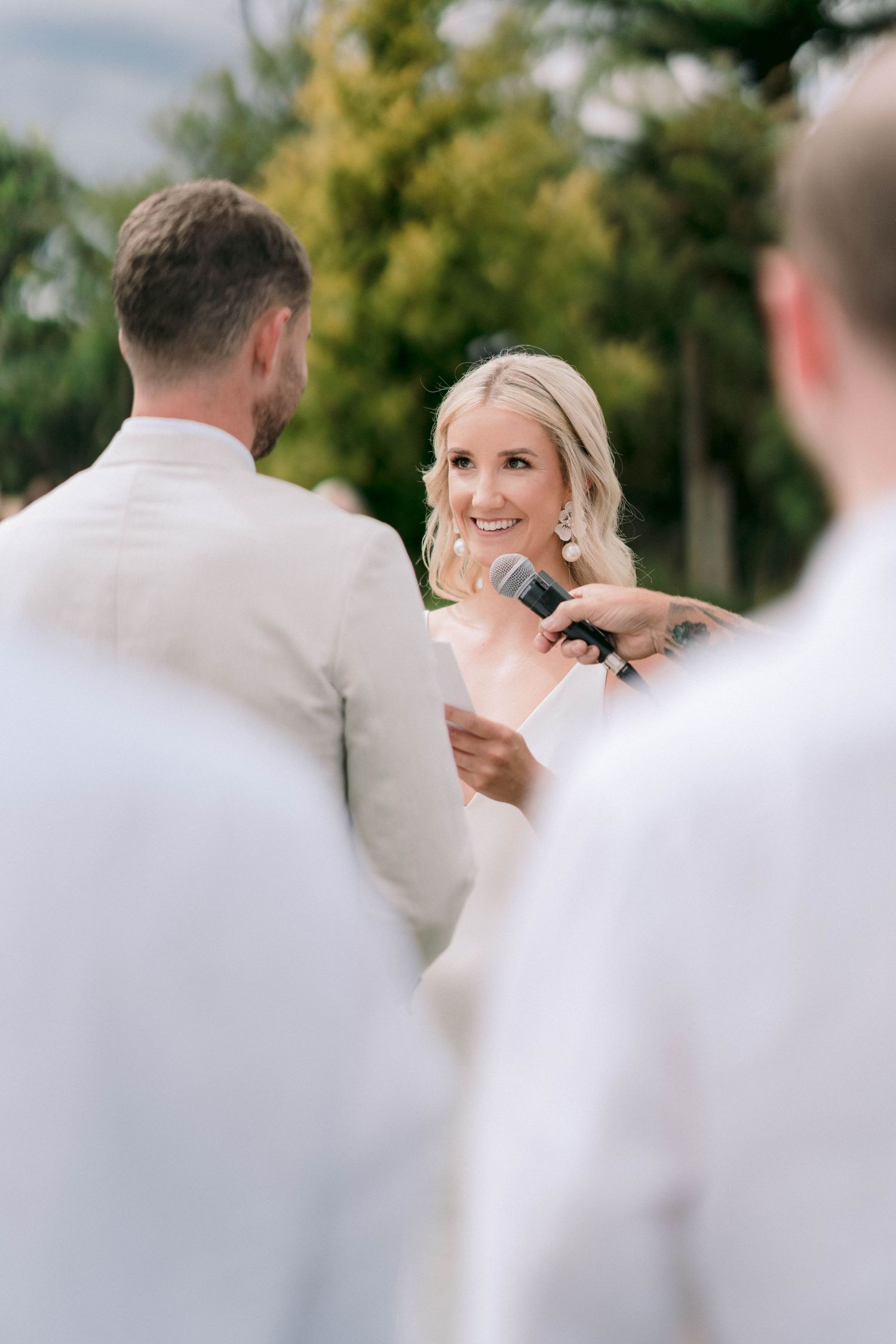 Wedding ceremony moment outdoors with guests in white attire.